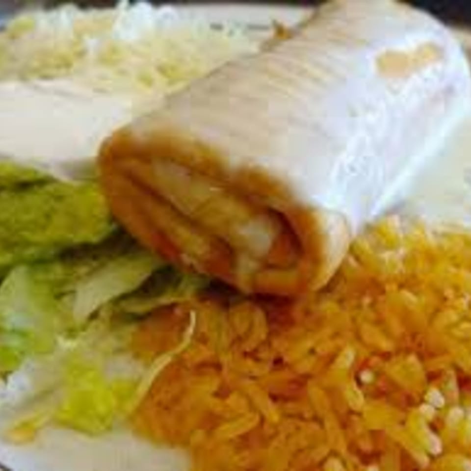 A Kings Roadhouse Bar & Grill burrito covered in white sauce, with rice, guacamole, and shredded cheese.