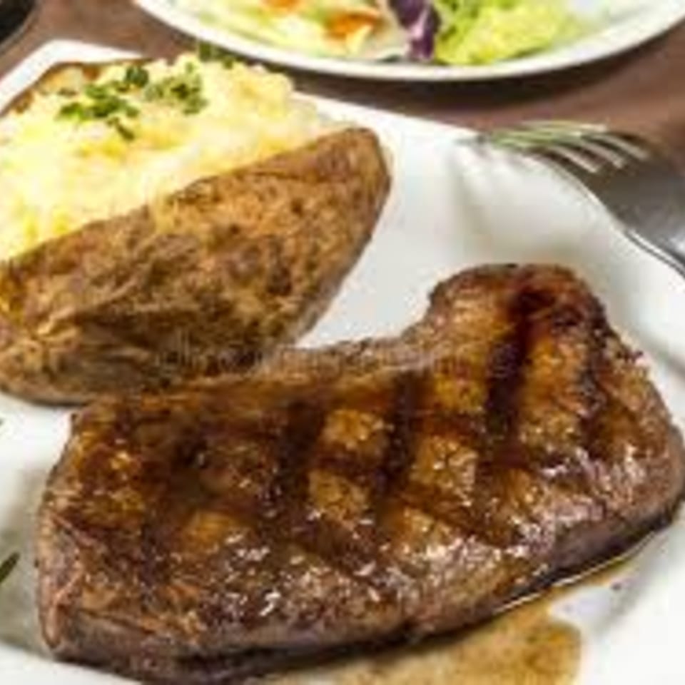 Kings Roadhouse Bar & Grill steak entree with a baked potato and a side salad.