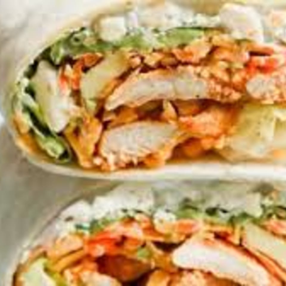 Two halves of a Kings Roadhouse Bar & Grill chicken wrap, filled with lettuce, cheese, and buffalo chicken.